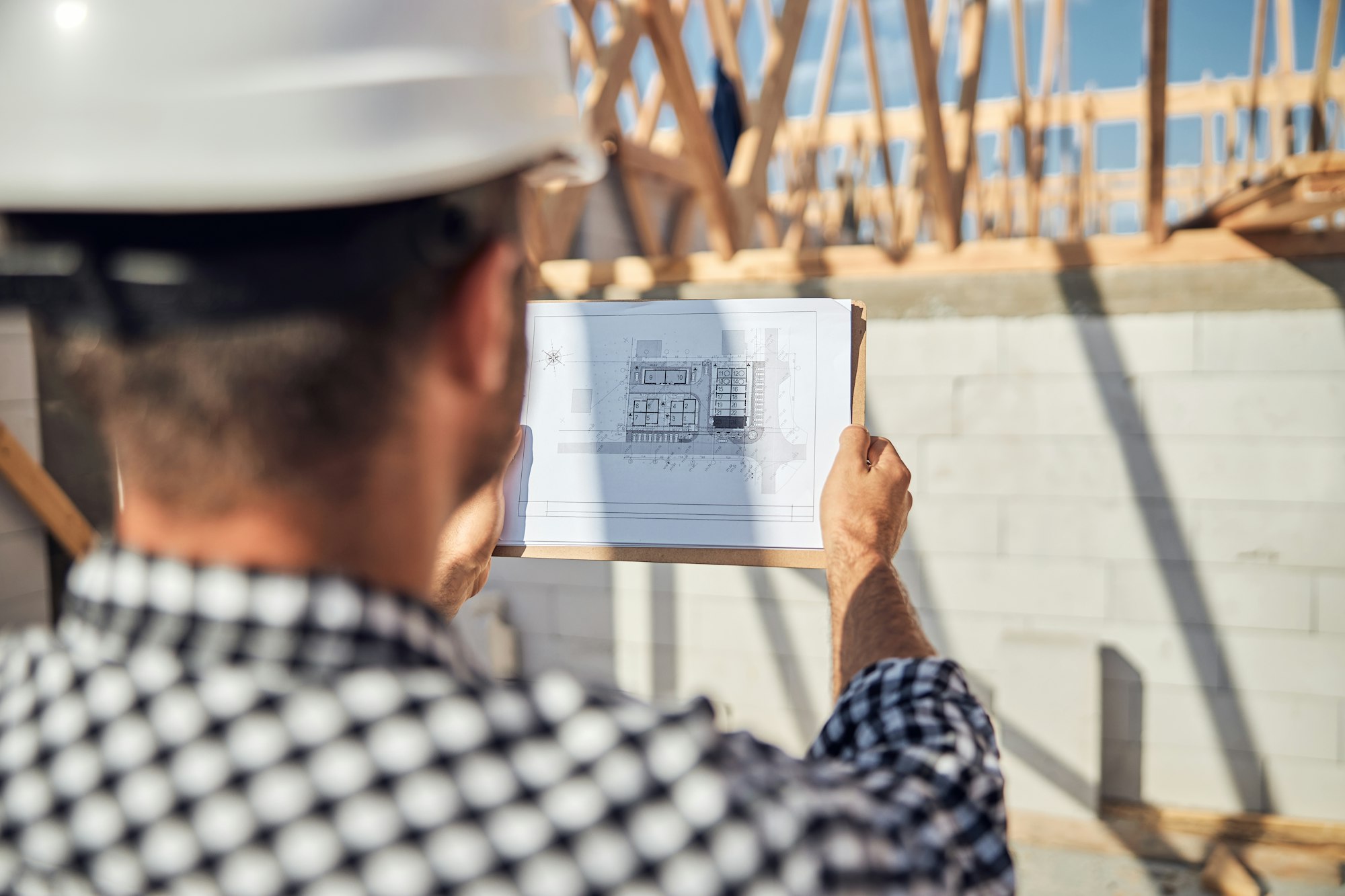 Qualified construction supervisor checking building whiteprints at construction site